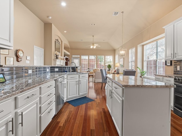 kitchen featuring white cabinetry, lofted ceiling, hanging light fixtures, a center island, and stainless steel dishwasher