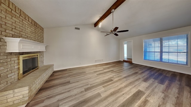 unfurnished living room featuring a brick fireplace, vaulted ceiling with beams, hardwood / wood-style floors, and ceiling fan