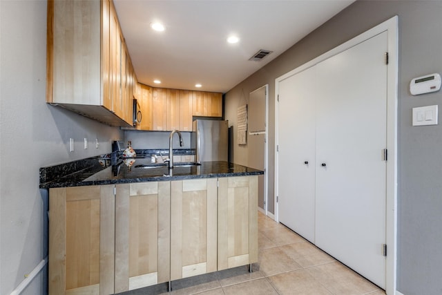 kitchen featuring light brown cabinetry, sink, dark stone countertops, kitchen peninsula, and stainless steel appliances