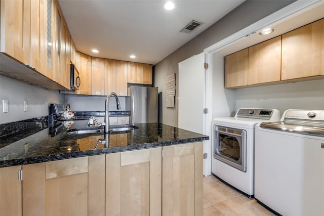 kitchen with sink, light brown cabinetry, stainless steel fridge, dark stone countertops, and separate washer and dryer