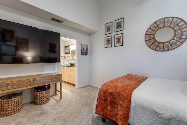 bedroom with ensuite bathroom and light carpet