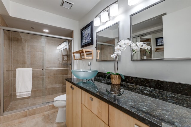 bathroom with vanity, toilet, a shower with shower door, and tile patterned flooring