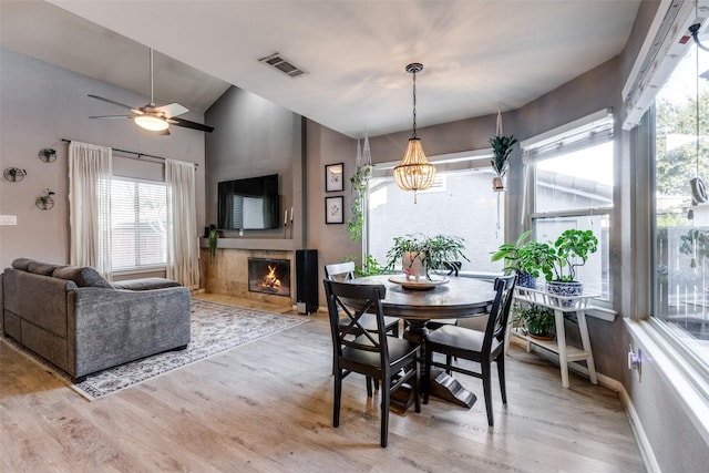 dining space with ceiling fan, vaulted ceiling, and light hardwood / wood-style flooring