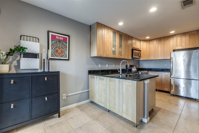 kitchen with sink, dark stone counters, light tile patterned floors, kitchen peninsula, and stainless steel appliances