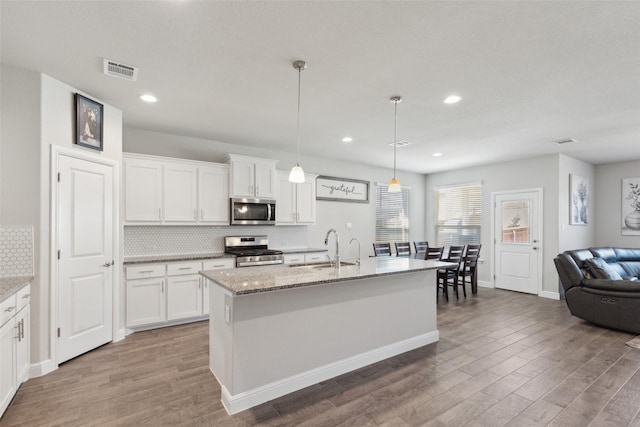 kitchen with white cabinetry, pendant lighting, a center island with sink, and appliances with stainless steel finishes