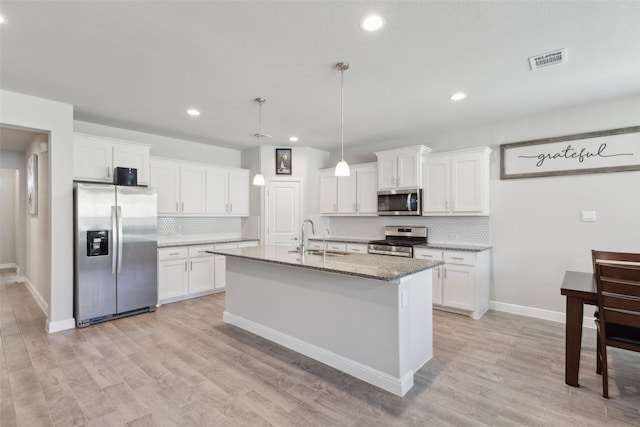 kitchen featuring stone countertops, sink, white cabinets, a kitchen island with sink, and stainless steel appliances