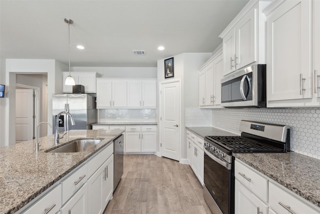 kitchen featuring pendant lighting, sink, white cabinets, light stone counters, and stainless steel appliances