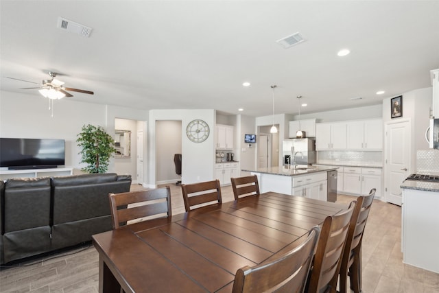 dining space with sink, light hardwood / wood-style floors, and ceiling fan