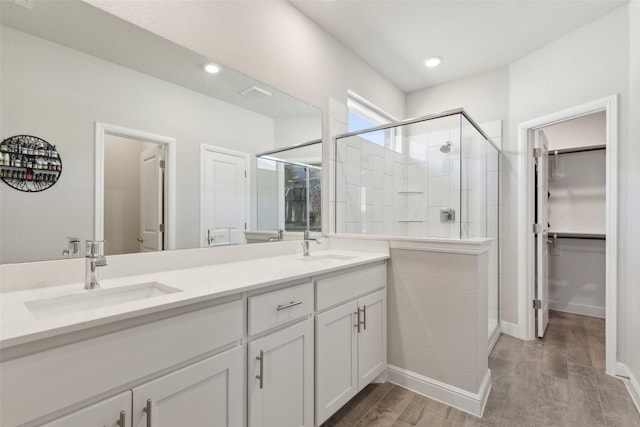 bathroom with walk in shower, vanity, and hardwood / wood-style floors