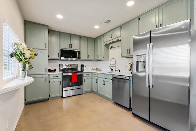 kitchen with stainless steel appliances, sink, and green cabinetry