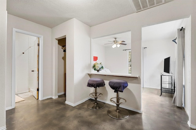 kitchen with ceiling fan, a breakfast bar, a textured ceiling, and kitchen peninsula