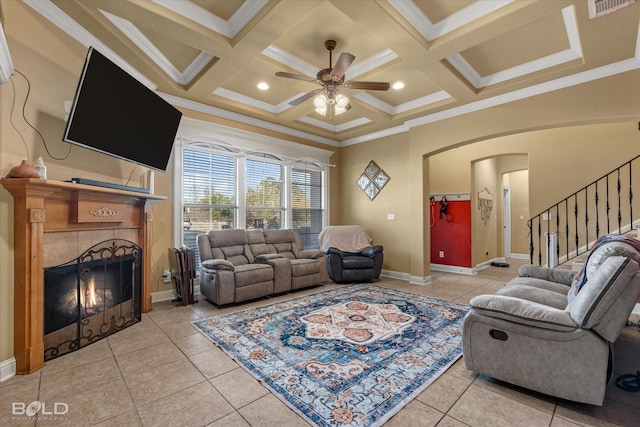 tiled living room featuring crown molding, ceiling fan, coffered ceiling, a fireplace, and beamed ceiling