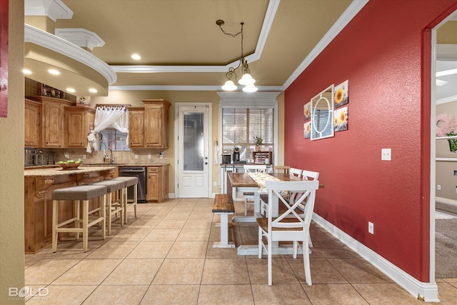 dining room with a tray ceiling, light tile patterned floors, crown molding, and sink