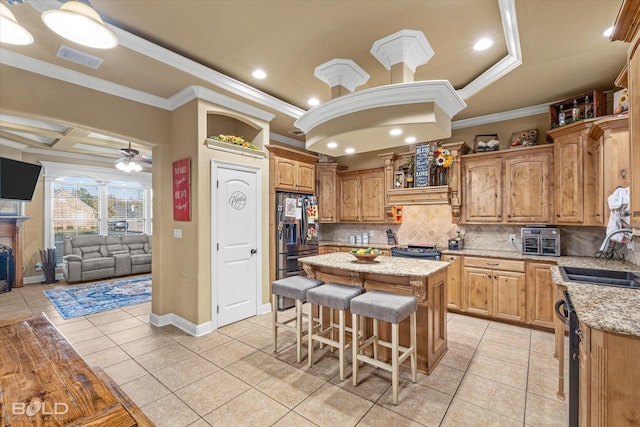 kitchen featuring sink, light tile patterned floors, ornamental molding, and a center island