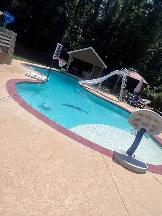 view of swimming pool with a patio, a water slide, and a diving board