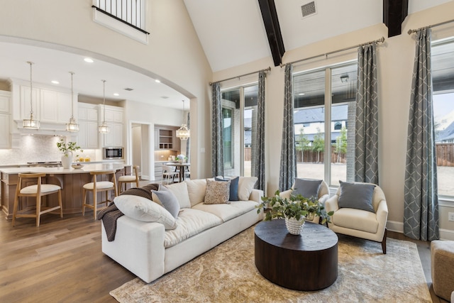 living room featuring beam ceiling, high vaulted ceiling, and light hardwood / wood-style flooring