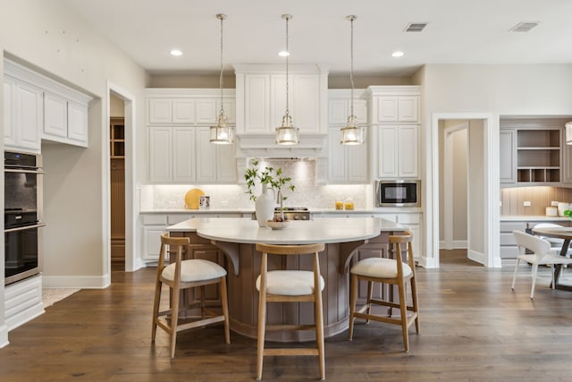 kitchen featuring stainless steel appliances, tasteful backsplash, white cabinets, a kitchen island, and decorative light fixtures