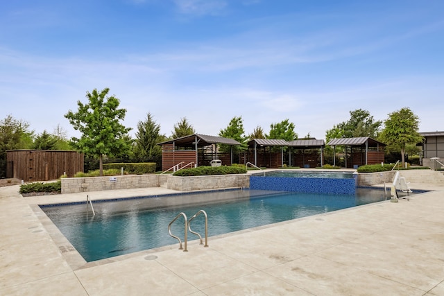 view of swimming pool featuring a patio, pool water feature, and an outbuilding