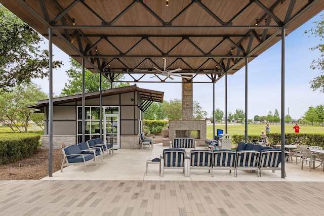 view of patio featuring ceiling fan, a gazebo, and an outdoor living space with a fireplace