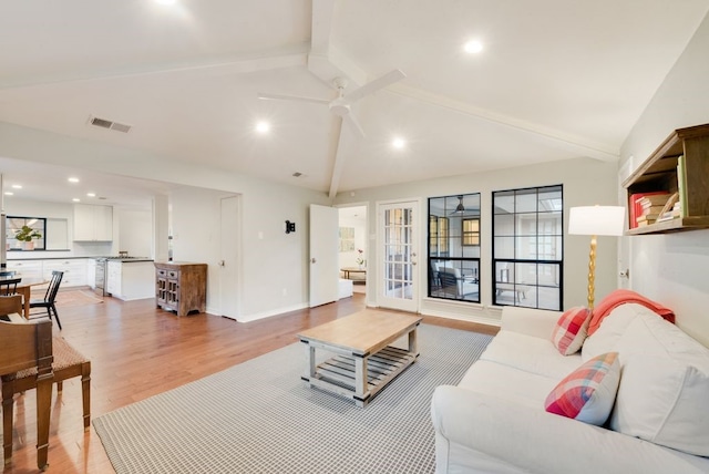 living room with french doors, ceiling fan, light hardwood / wood-style floors, and vaulted ceiling with beams