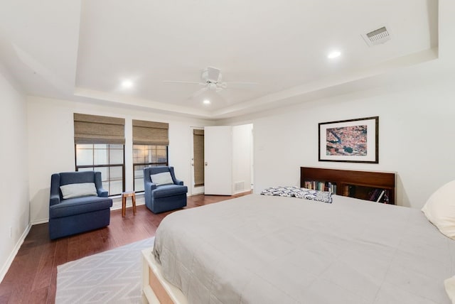 bedroom with ceiling fan, wood-type flooring, and a tray ceiling