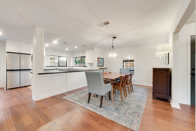 dining area featuring an inviting chandelier, light hardwood / wood-style floors, and a wealth of natural light