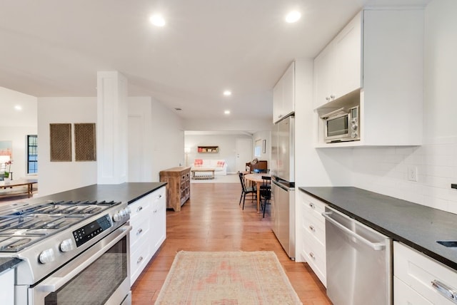 kitchen featuring tasteful backsplash, stainless steel appliances, light hardwood / wood-style floors, and white cabinets