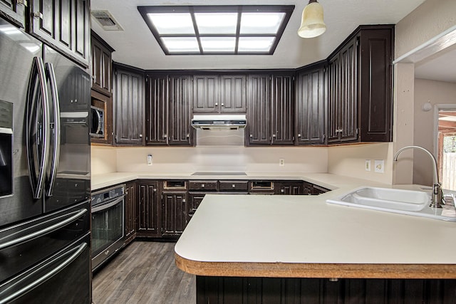 kitchen featuring decorative light fixtures, sink, dark hardwood / wood-style flooring, kitchen peninsula, and stainless steel appliances