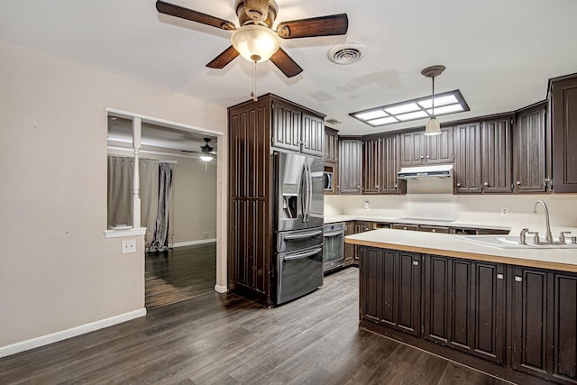 kitchen with sink, dark wood-type flooring, appliances with stainless steel finishes, dark brown cabinets, and decorative light fixtures