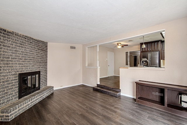 unfurnished living room featuring dark hardwood / wood-style floors, ceiling fan, and a fireplace