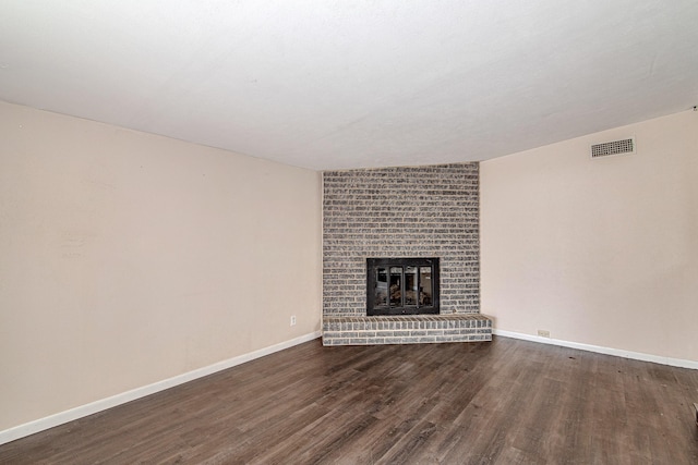 unfurnished living room featuring dark wood-type flooring and a fireplace