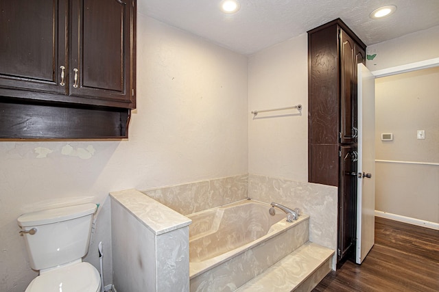 bathroom featuring wood-type flooring, a tub, a textured ceiling, and toilet