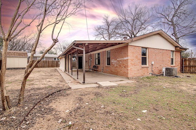 back house at dusk with a storage unit, cooling unit, and a patio area