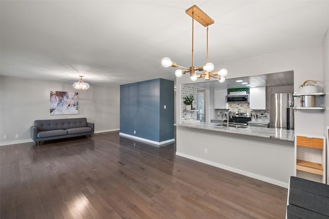 kitchen with hanging light fixtures, appliances with stainless steel finishes, a chandelier, and kitchen peninsula