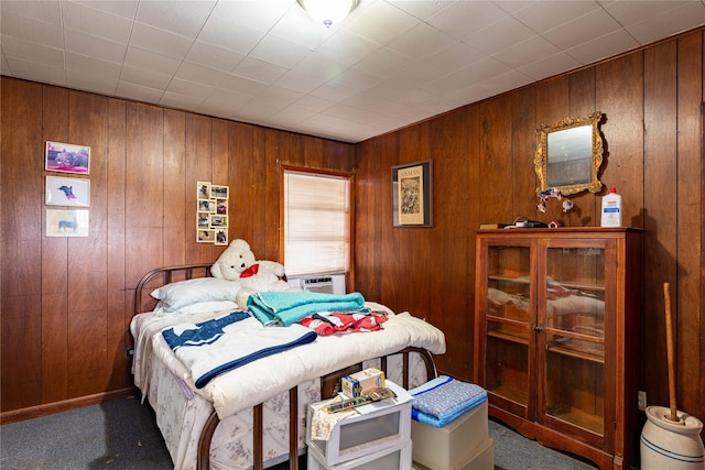 bedroom with wooden walls and dark colored carpet