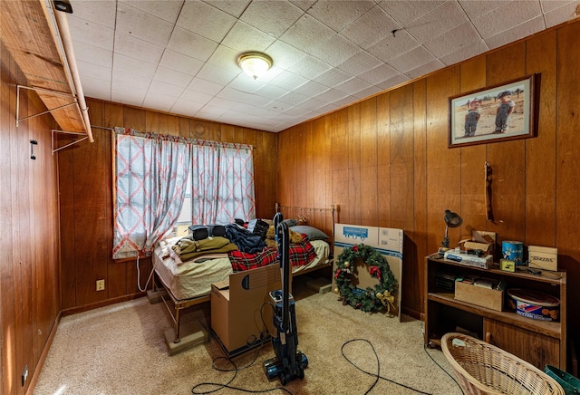 bedroom featuring wooden walls and light colored carpet