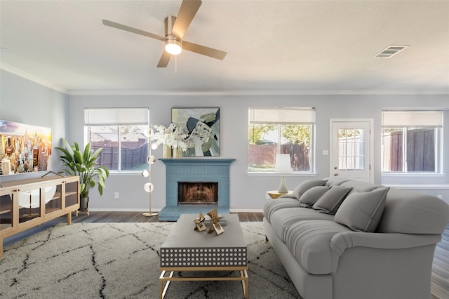 living room with crown molding, plenty of natural light, wood-type flooring, and a brick fireplace