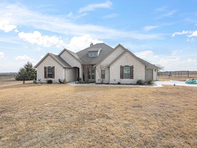 french country style house featuring a garage and a front lawn