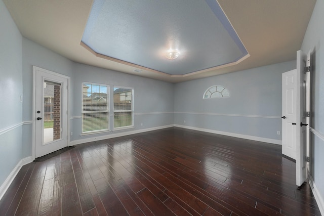 empty room featuring dark hardwood / wood-style flooring, a raised ceiling, and a textured ceiling