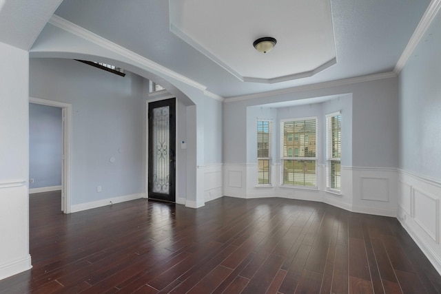 empty room with a raised ceiling, ornamental molding, and dark hardwood / wood-style floors