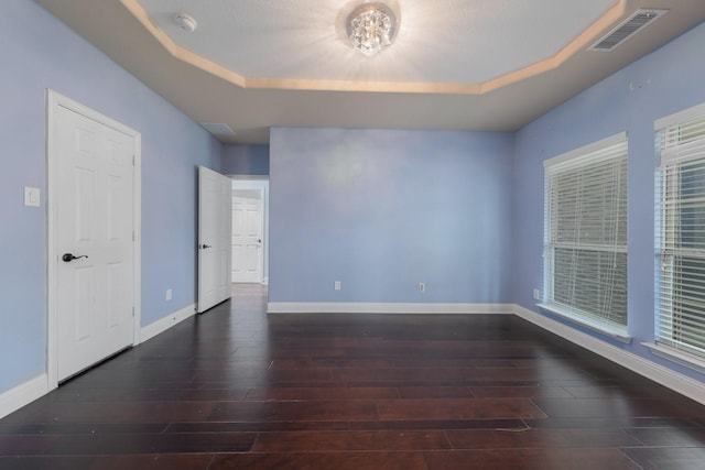 unfurnished room featuring a raised ceiling and dark wood-type flooring