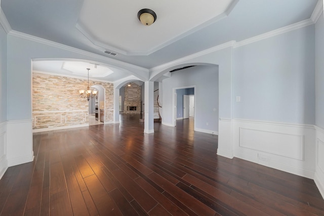 unfurnished living room featuring dark wood-type flooring, a tray ceiling, crown molding, and a notable chandelier