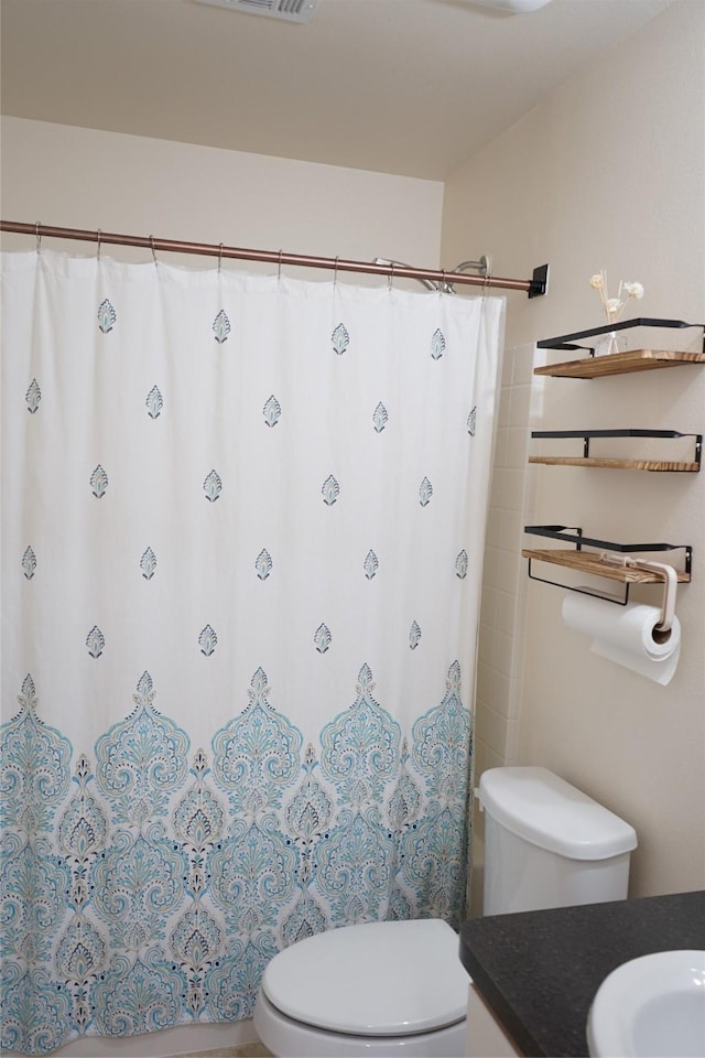 bathroom featuring toilet, a shower with shower curtain, and vanity