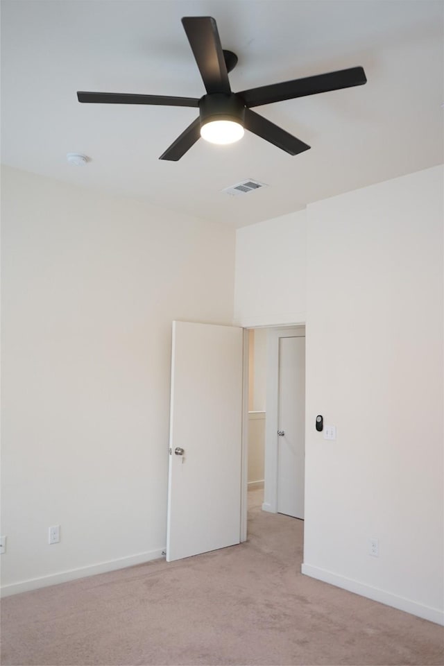 unfurnished room featuring baseboards, visible vents, a ceiling fan, and light carpet