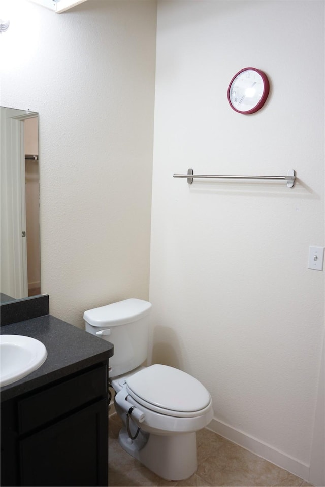 bathroom featuring toilet, vanity, baseboards, and tile patterned flooring
