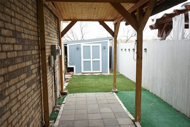 view of patio with an outdoor structure, a fenced backyard, and a storage unit