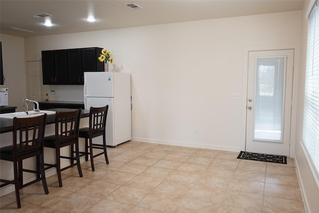 kitchen with visible vents, white appliances, a kitchen bar, a sink, and dark cabinets