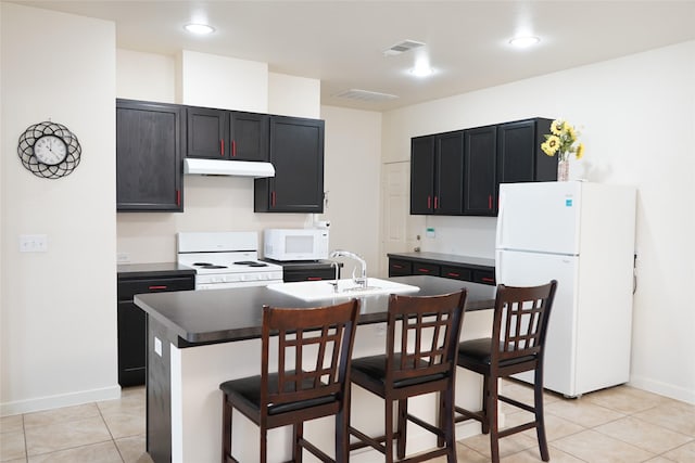 kitchen featuring white appliances, under cabinet range hood, a sink, an island with sink, and a kitchen breakfast bar