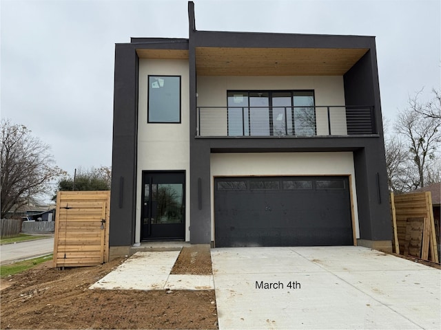 modern home with stucco siding, fence, concrete driveway, an attached garage, and a balcony