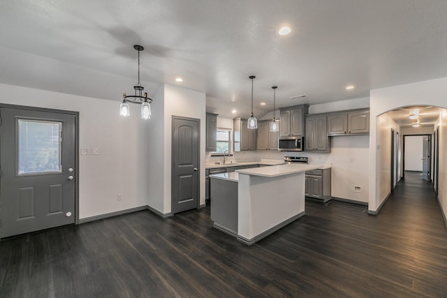 kitchen with gray cabinetry, light countertops, hanging light fixtures, a center island, and stainless steel microwave